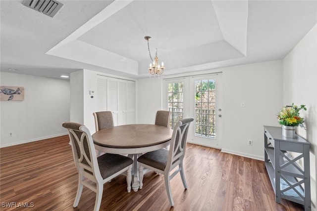 dining room featuring a raised ceiling, wood finished floors, and visible vents