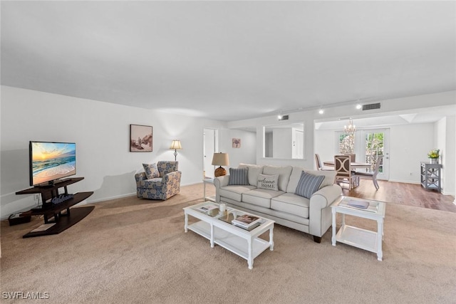 living area featuring visible vents, rail lighting, baseboards, and an inviting chandelier