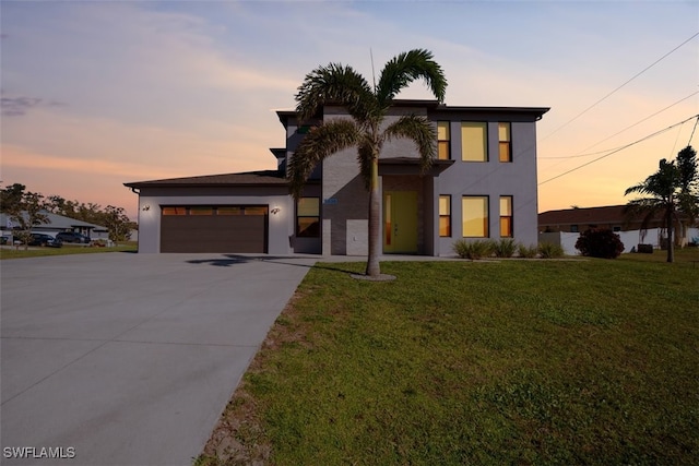 modern home with stucco siding, an attached garage, concrete driveway, and a front yard