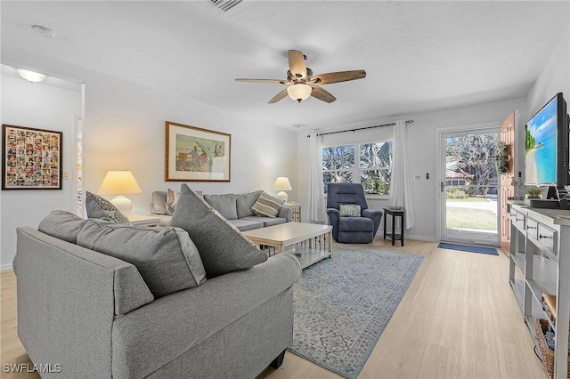 living room featuring ceiling fan, baseboards, and light wood-style floors