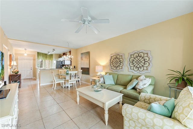 living room with baseboards, light tile patterned flooring, and ceiling fan with notable chandelier