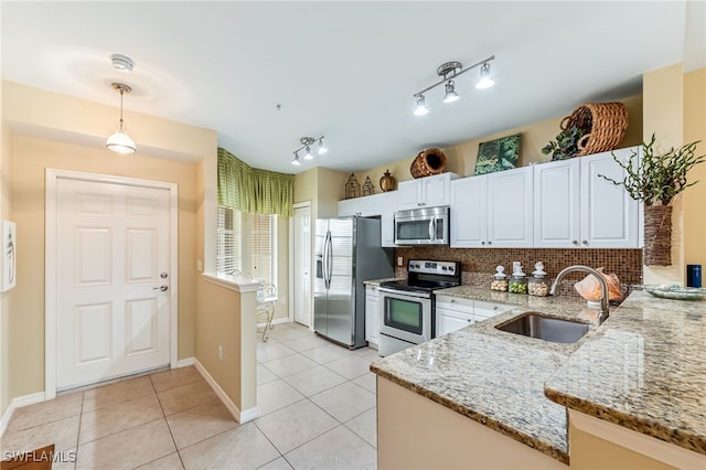 kitchen featuring tasteful backsplash, decorative light fixtures, light tile patterned floors, stainless steel appliances, and a sink