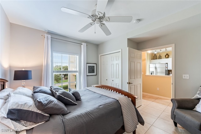 bedroom featuring a closet, stainless steel fridge with ice dispenser, light tile patterned floors, baseboards, and ceiling fan