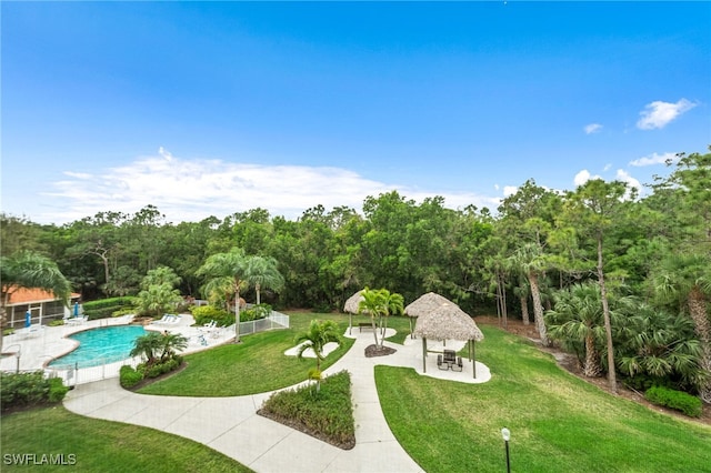 view of property's community with fence, a gazebo, a swimming pool, a patio area, and a lawn