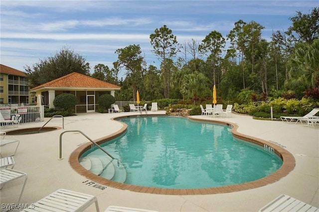 pool with a patio area, fence, and a sunroom