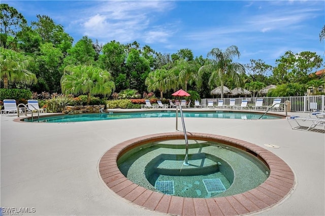 community pool featuring a hot tub, a patio, and fence