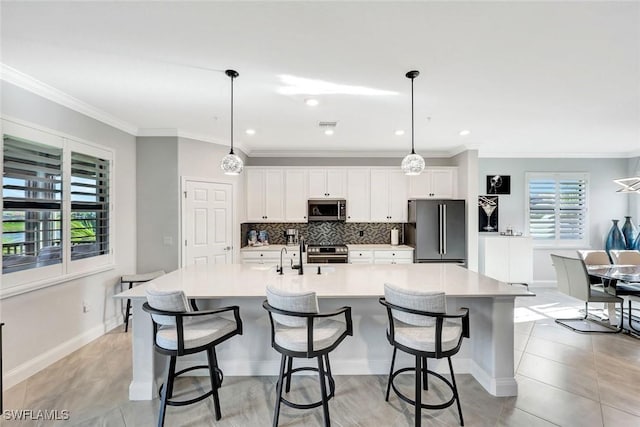 kitchen featuring tasteful backsplash, a large island with sink, stainless steel appliances, and light countertops