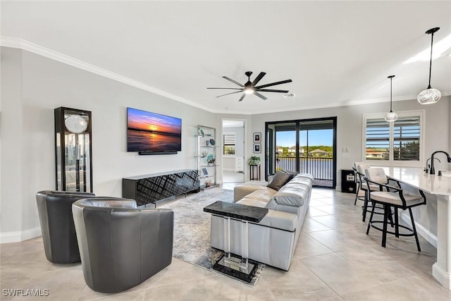 living area featuring light tile patterned floors, ceiling fan, baseboards, and ornamental molding