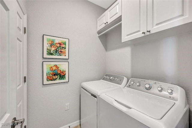 washroom featuring washer and clothes dryer, cabinet space, and baseboards