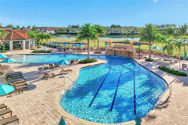 community pool with a water view, fence, and a patio area