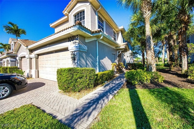 view of property exterior featuring a tiled roof, stucco siding, an attached garage, and decorative driveway