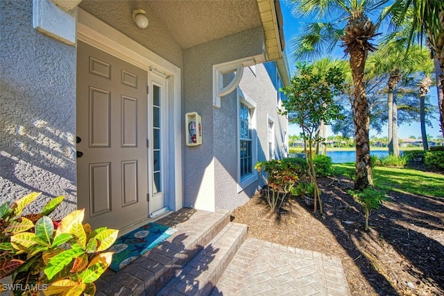 view of exterior entry with stucco siding and a water view