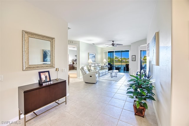 living area featuring light tile patterned floors, visible vents, baseboards, and a ceiling fan