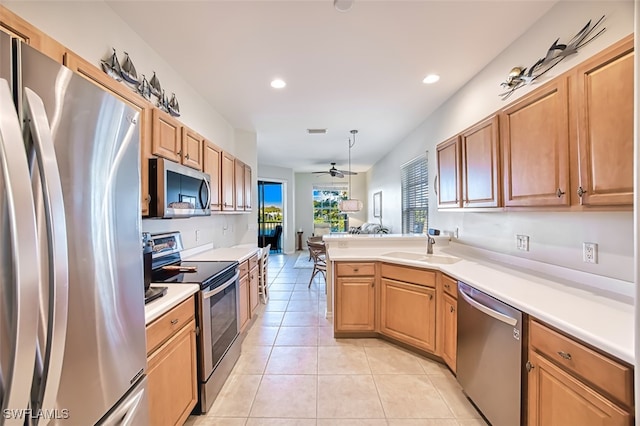 kitchen with a sink, stainless steel appliances, a peninsula, light countertops, and light tile patterned floors