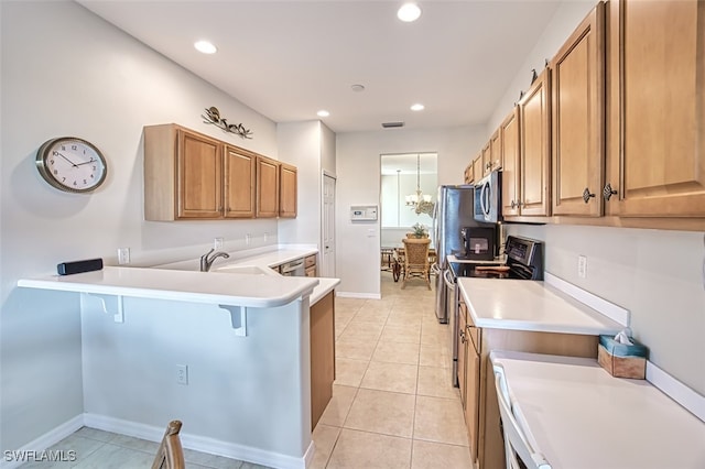 kitchen with light tile patterned floors, a peninsula, stainless steel appliances, light countertops, and a kitchen bar