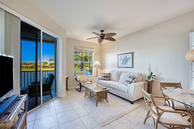 living area with light tile patterned flooring, baseboards, and a ceiling fan