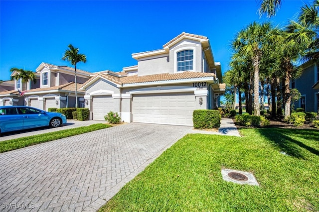 view of front of house featuring a front yard, a tiled roof, decorative driveway, and stucco siding