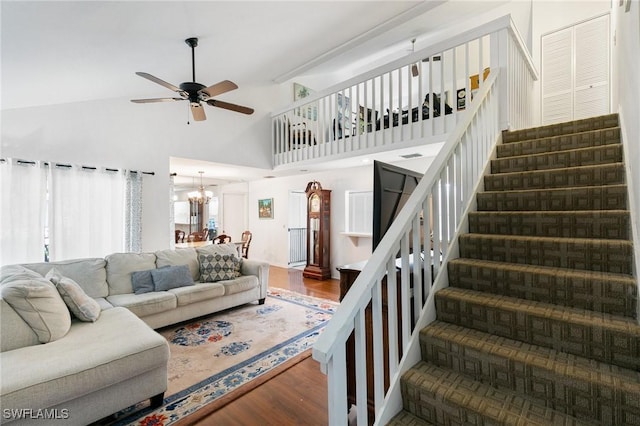 living area featuring ceiling fan with notable chandelier, stairway, wood finished floors, and high vaulted ceiling