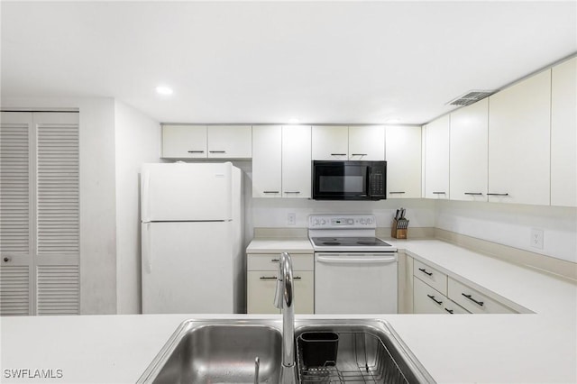 kitchen with white appliances, visible vents, a sink, light countertops, and white cabinetry