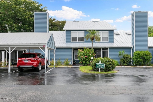 townhome / multi-family property featuring uncovered parking, a chimney, and metal roof