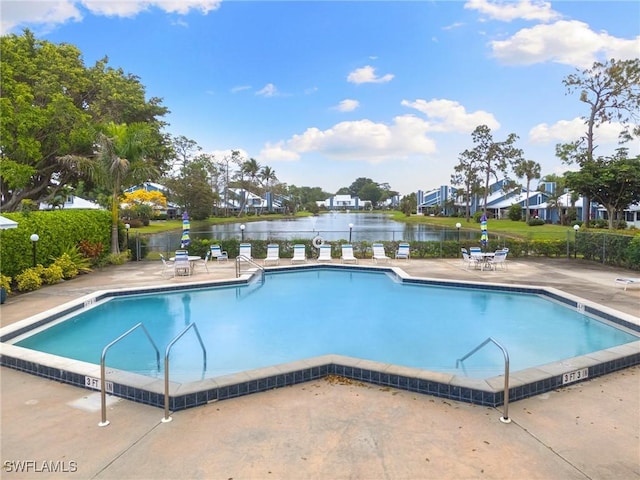 view of swimming pool with a patio, fence, and a water view