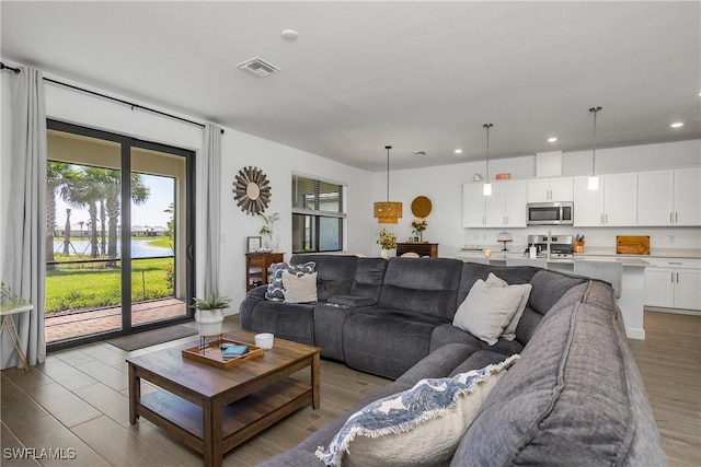 living room with recessed lighting, light wood-type flooring, and visible vents