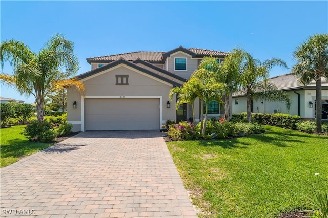 mediterranean / spanish-style home with stucco siding, a front lawn, a tile roof, decorative driveway, and an attached garage