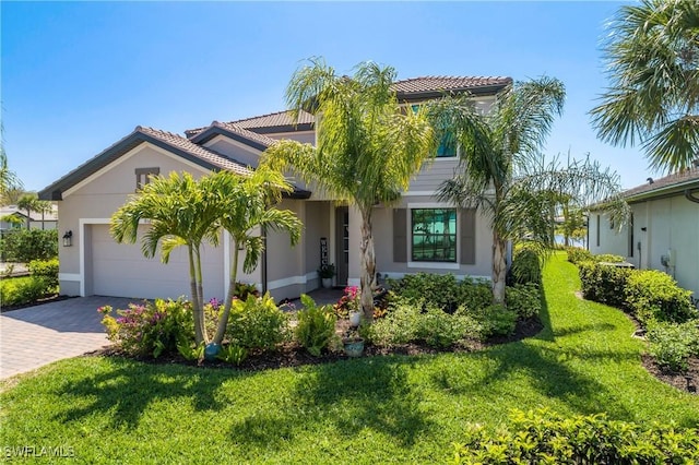 mediterranean / spanish-style home with stucco siding, an attached garage, decorative driveway, and a front yard