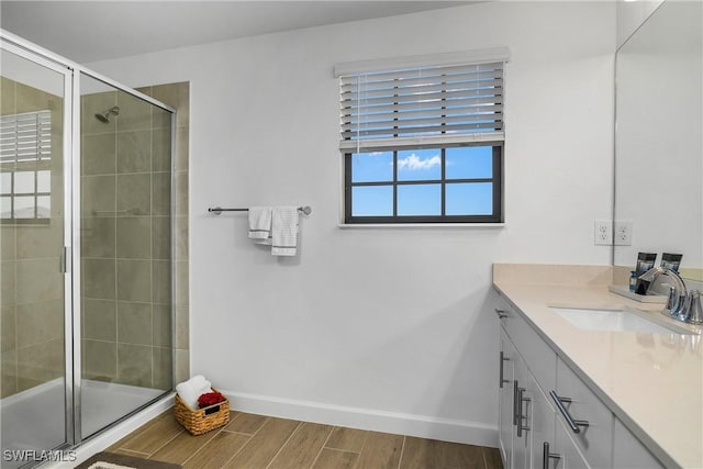 bathroom featuring a stall shower, baseboards, wood finished floors, and vanity