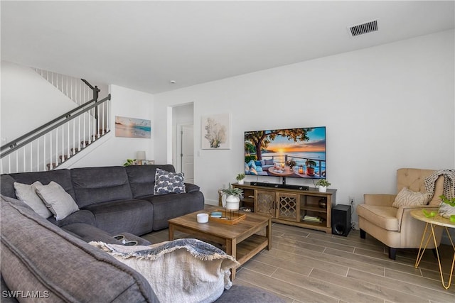 living room featuring visible vents, stairway, and wood finish floors