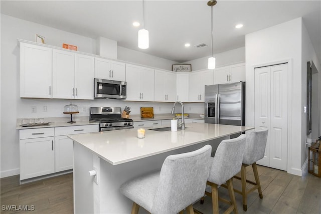 kitchen featuring dark wood-style flooring, white cabinets, appliances with stainless steel finishes, and a sink