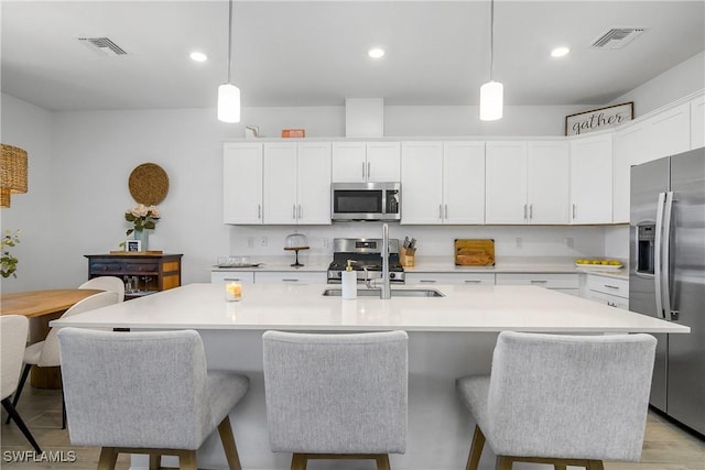 kitchen featuring pendant lighting, stainless steel appliances, visible vents, and white cabinets