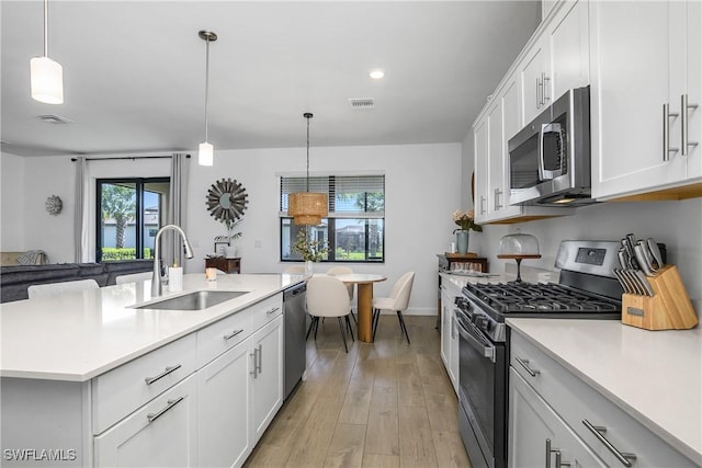 kitchen featuring light wood finished floors, visible vents, light countertops, stainless steel appliances, and a sink