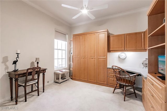 office space with built in desk, light colored carpet, ceiling fan, and ornamental molding