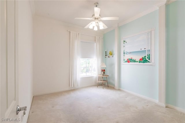 carpeted empty room featuring baseboards, ceiling fan, and crown molding