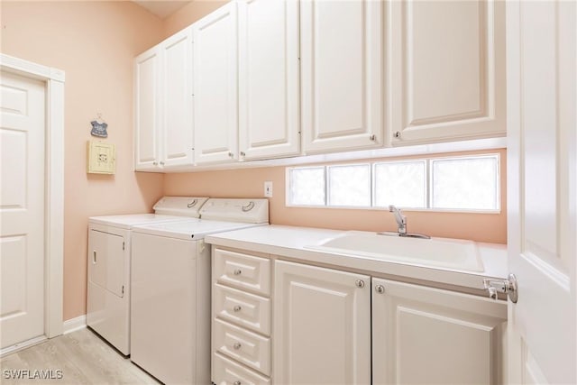 clothes washing area with light wood-style flooring, cabinet space, independent washer and dryer, and a sink