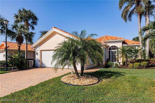 mediterranean / spanish-style house with a tiled roof, a front yard, stucco siding, decorative driveway, and a garage