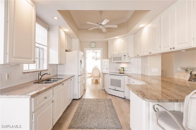 kitchen with white appliances, a peninsula, a sink, white cabinetry, and a raised ceiling