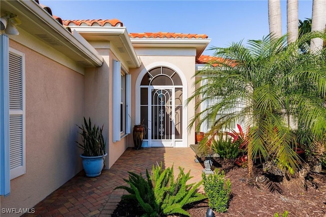 entrance to property featuring a tiled roof and stucco siding