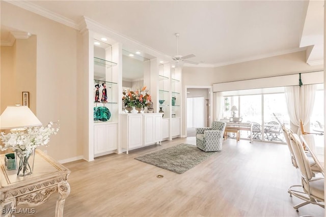 foyer featuring light wood finished floors, crown molding, and a ceiling fan