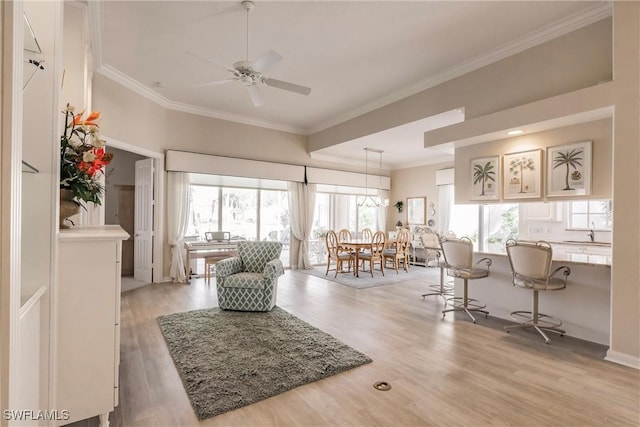 living area featuring light wood-type flooring, ceiling fan, and crown molding