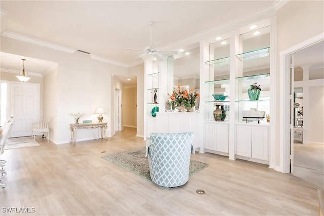 interior space featuring visible vents, baseboards, light wood-style flooring, ceiling fan, and crown molding