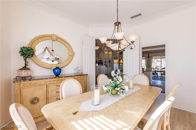 dining area featuring visible vents, ornamental molding, light wood finished floors, baseboards, and a chandelier