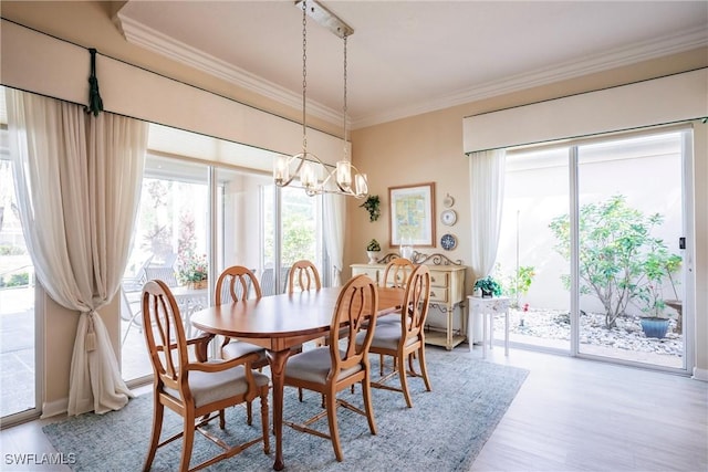 dining space with light wood-type flooring, a notable chandelier, and crown molding