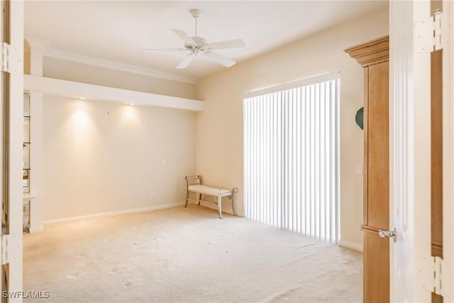 empty room with light carpet, baseboards, ceiling fan, and ornamental molding