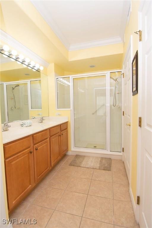 bathroom featuring tile patterned flooring, double vanity, ornamental molding, a stall shower, and a sink