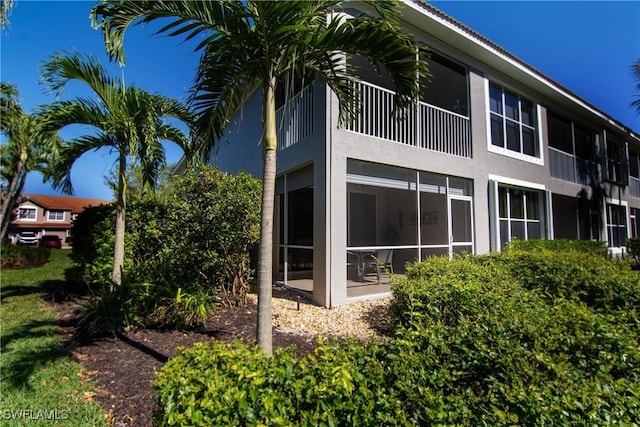 rear view of house featuring stucco siding and a sunroom