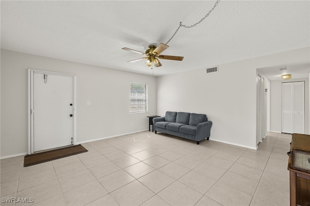 living area with light tile patterned floors, visible vents, a textured ceiling, and ceiling fan