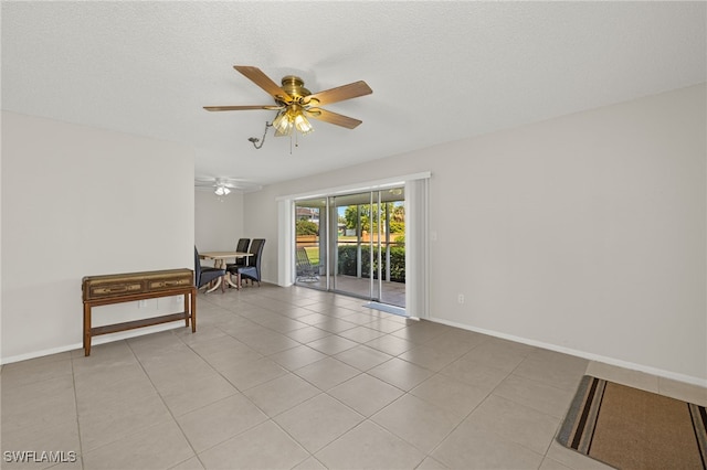 unfurnished room featuring light tile patterned floors, baseboards, a textured ceiling, and a ceiling fan