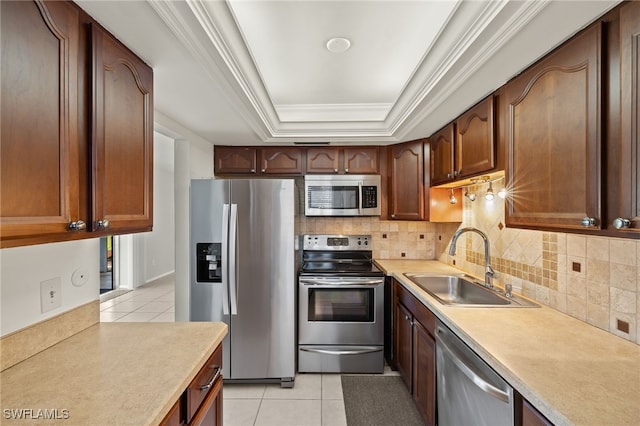 kitchen featuring a tray ceiling, light tile patterned flooring, a sink, stainless steel appliances, and light countertops